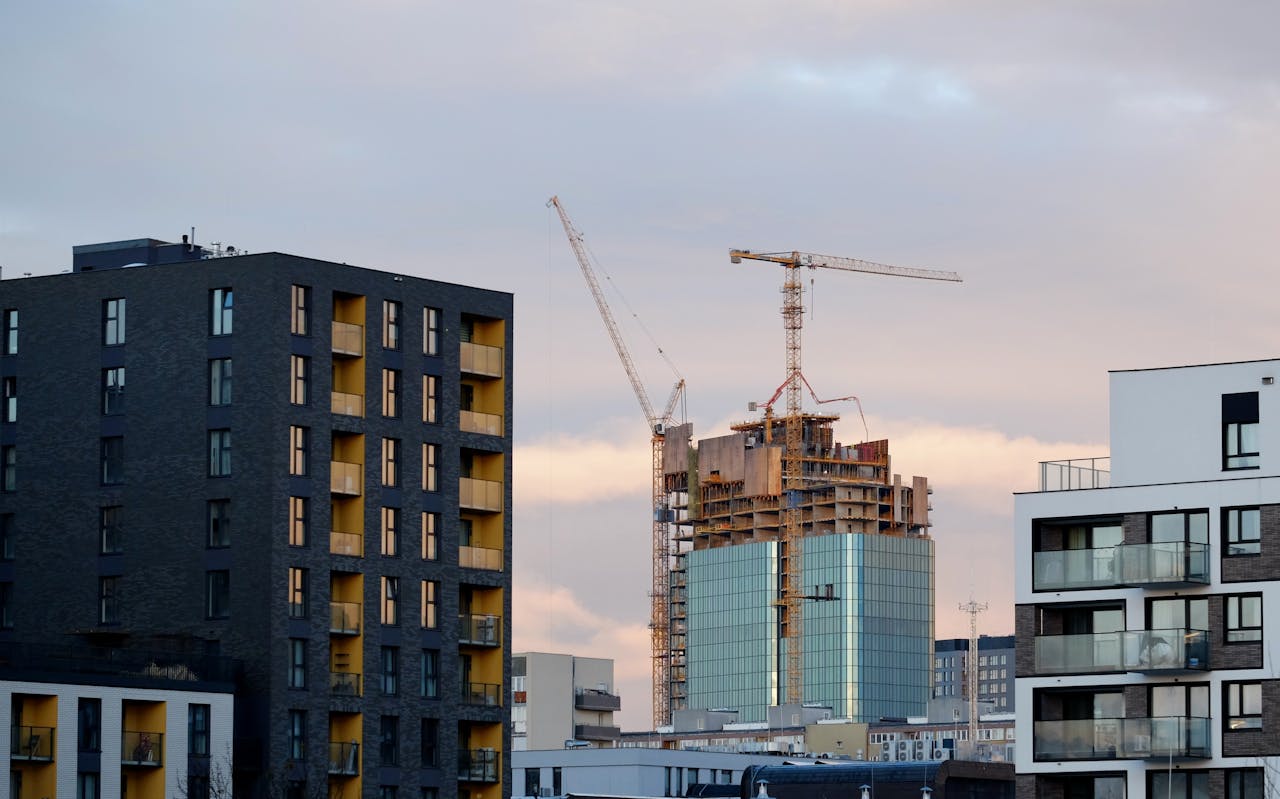 High-rise buildings and cranes in urban skyline at sunset.