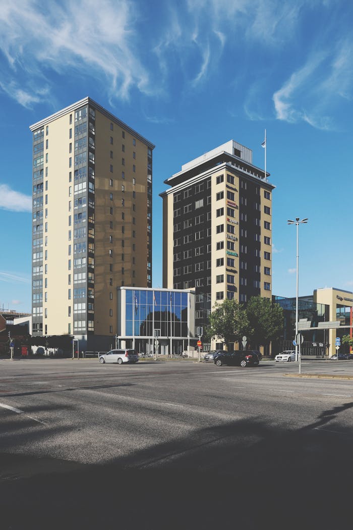 our-services-02 Two high-rise buildings in a modern urban environment under a clear blue sky.